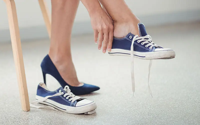 woman changing out of high heels and putting on sneakers