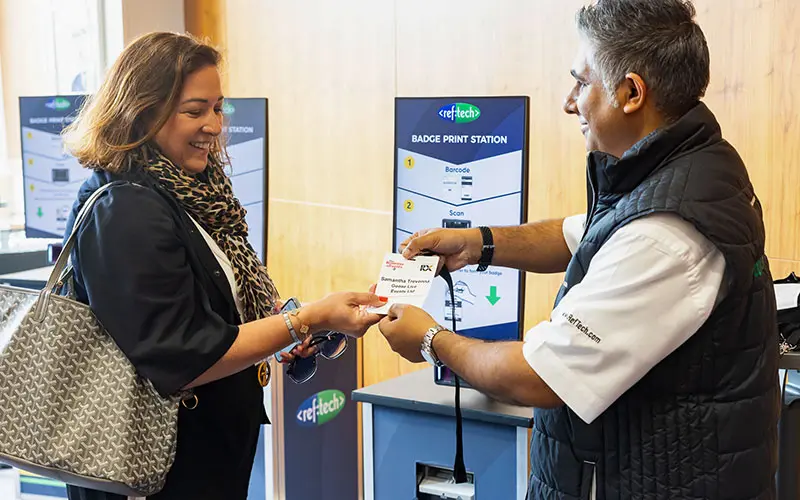 RefTech staff handing a badge to an attendee at Business of Events: Global Policy Forum