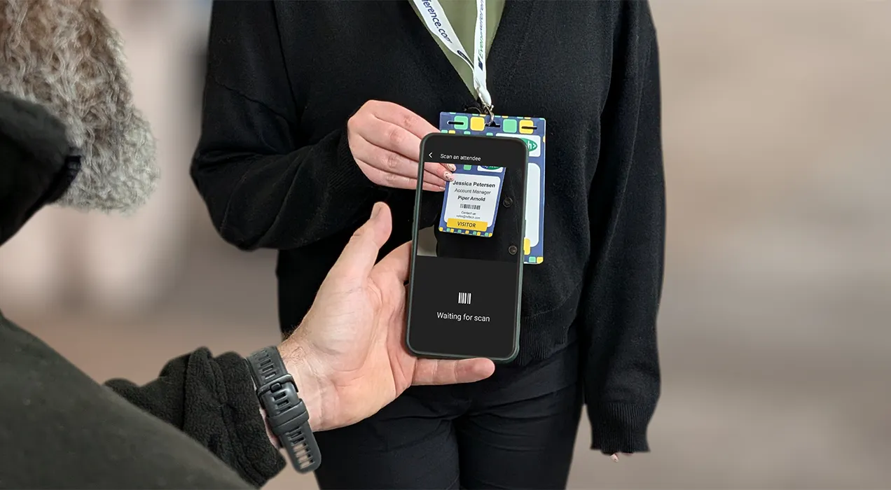 A man using the ContactScanning app on their smartphone to scan the badge a woman is wearing